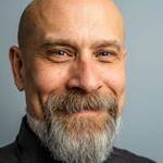 Close-up portrait of a mature bald man with a full beard, exuding confidence and style in a professional studio setting.