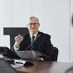 Senior businessman leading a professional discussion in a corporate meeting setting.